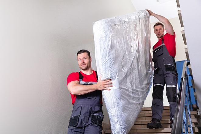 two workers lifting a box spring out of a bedroom in Blauvelt